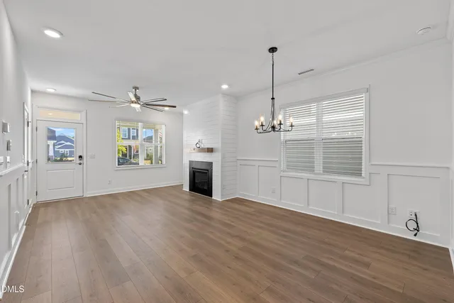 an empty room with wooden floor fireplace and windows