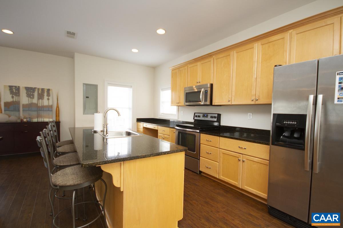 3232 Bergen Street Charlottesville, VA 22902 - Photo 24 of 31 a kitchen with stainless steel appliances granite countertop a stove a sink a microwave a dining table and chairs with wooden floor