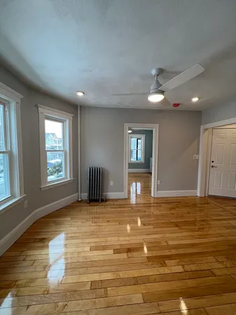 a view of an empty room with window and wooden floor