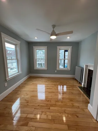 a view of an empty room with window and wooden floor