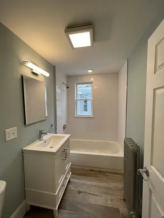 a bathroom with a tub sink and mirror