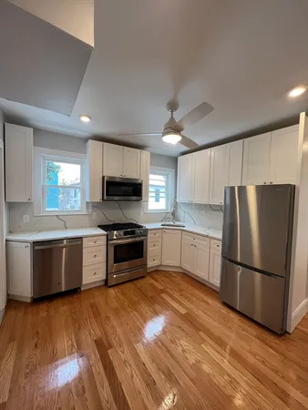 a kitchen with granite countertop a refrigerator stove and wooden floors