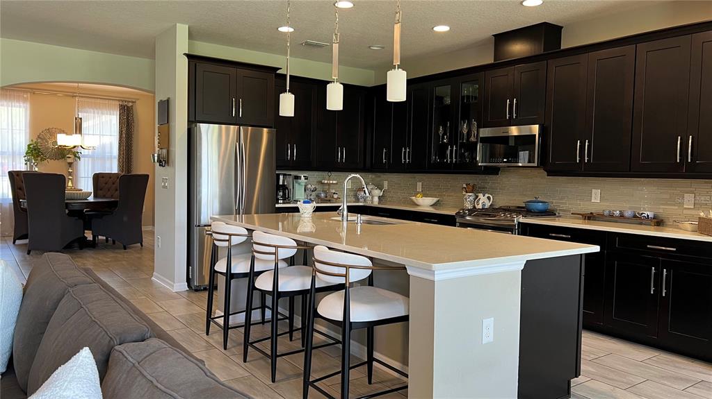714 Riviera Bella Drive DeBary, FL 32713 - Photo 15 of 50 a kitchen with stainless steel appliances kitchen island granite countertop a refrigerator a stove a sink and a microwave with wooden floor