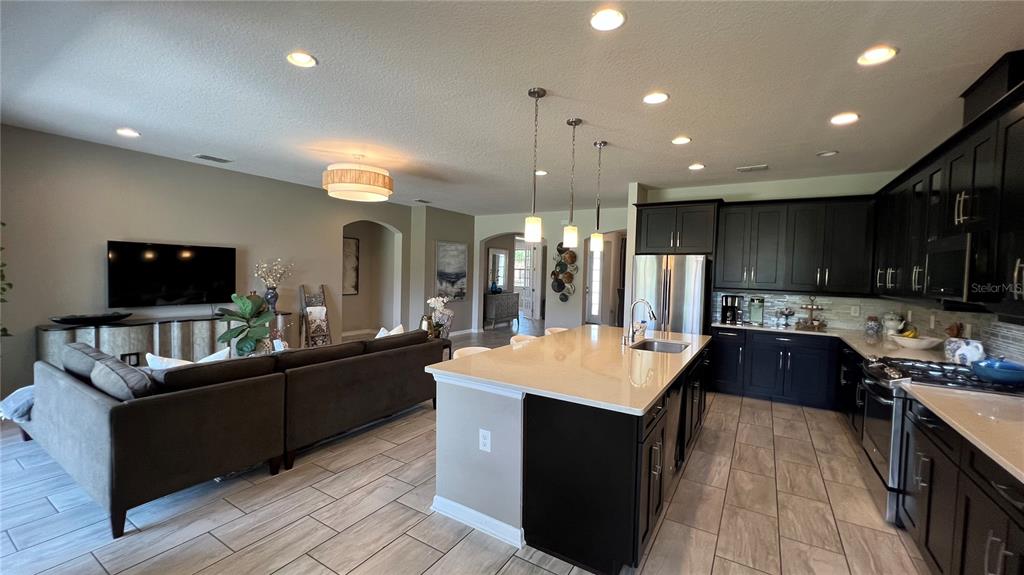 714 Riviera Bella Drive DeBary, FL 32713 - Photo 16 of 50 a large kitchen with stainless steel appliances a stove a sink dishwasher a refrigerator and a dining table with wooden floor
