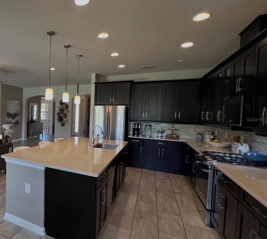714 Riviera Bella Drive DeBary, FL 32713 - Photo 18 of 50 a kitchen with stainless steel appliances granite countertop a sink a stove and a refrigerator