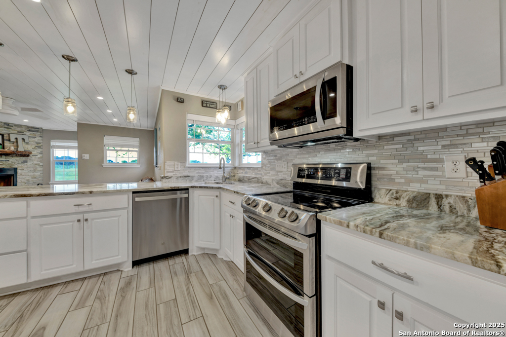 15592 Miller Road St. Hedwig, TX 78152 - Photo 11 of 47 a kitchen with stainless steel appliances granite countertop a stove a sink and a microwave