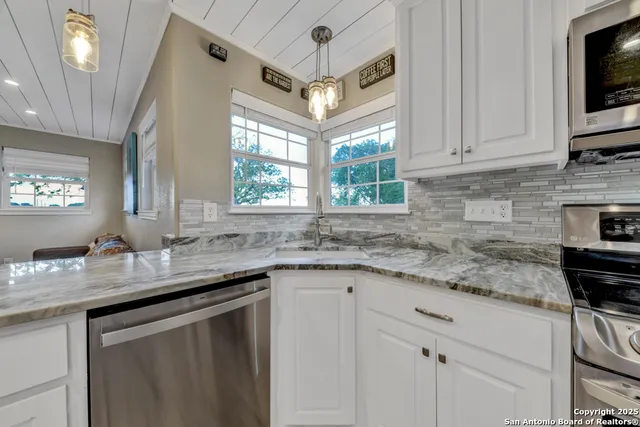 a kitchen with stainless steel appliances granite countertop a table chairs sink refrigerator and microwave