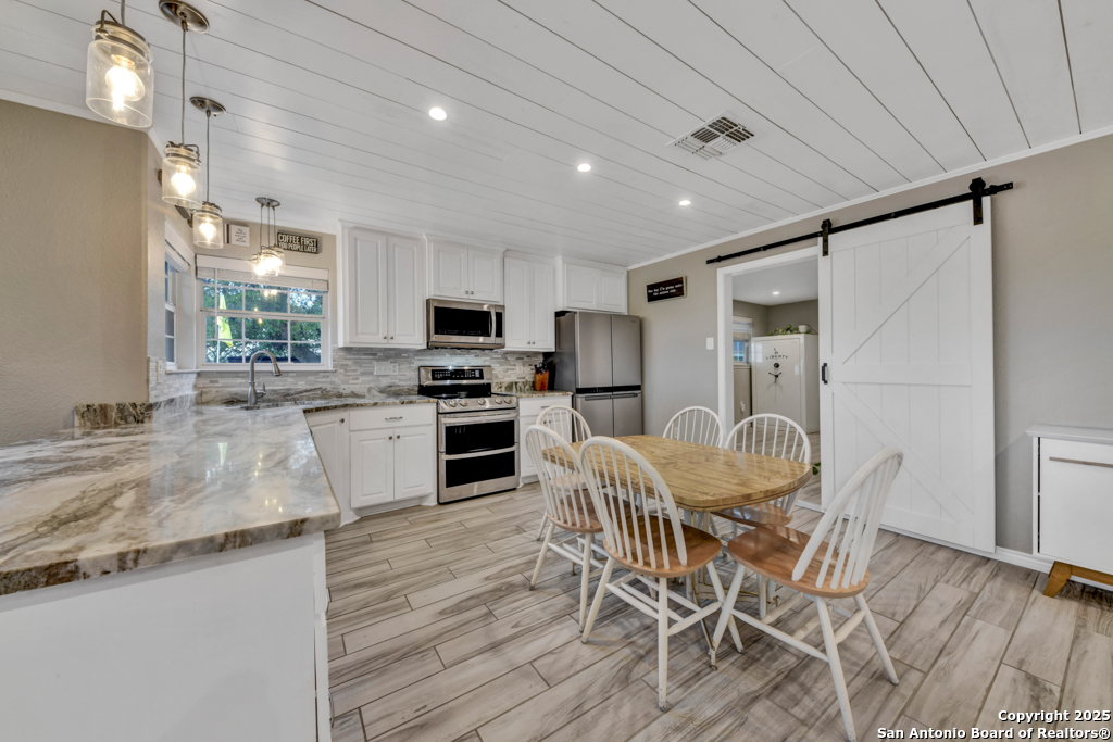 15592 Miller Road St. Hedwig, TX 78152 - Photo 13 of 47 a kitchen with stainless steel appliances granite countertop a table chairs sink refrigerator and microwave