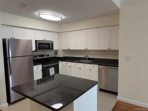 a kitchen with granite countertop a refrigerator a stove a sink dishwasher and a refrigerator
