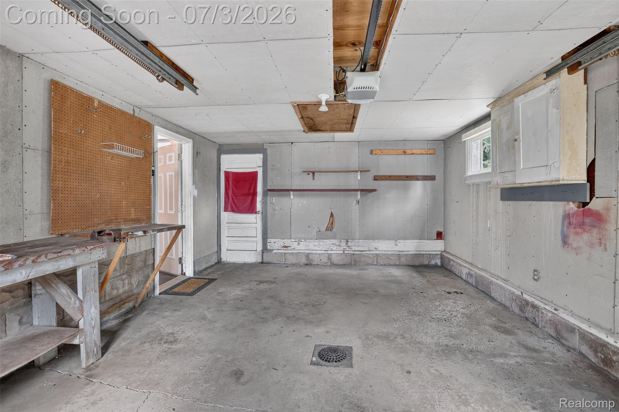 4322 Baker Road Bridgeport, MI 48722 - Photo 26 of 29 Spacious garage featuring a concrete floor with drain, built-in workbench, pegboard storage, and overhead garage door track