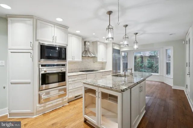 a kitchen with kitchen island granite countertop a stove and a wooden floor