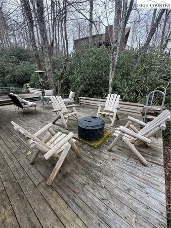 a view of a roof deck with table and chairs a barbeque with wooden floor and fence