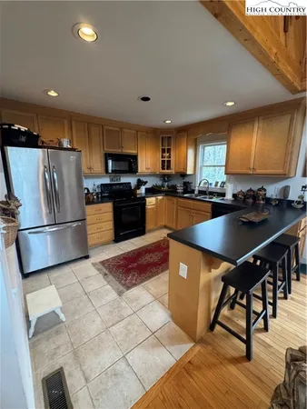 a kitchen with stainless steel appliances granite countertop a refrigerator a sink a stove a dining table and chairs