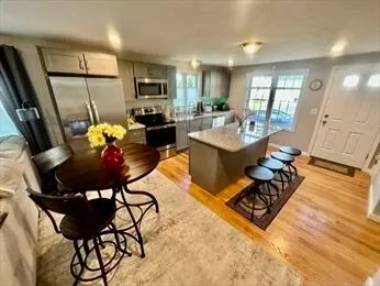a living room with furniture a rug kitchen view and a chandelier