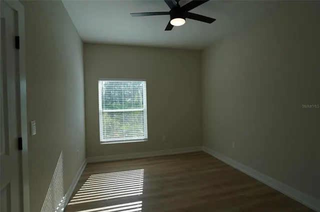 an empty room with wooden floor closet and windows