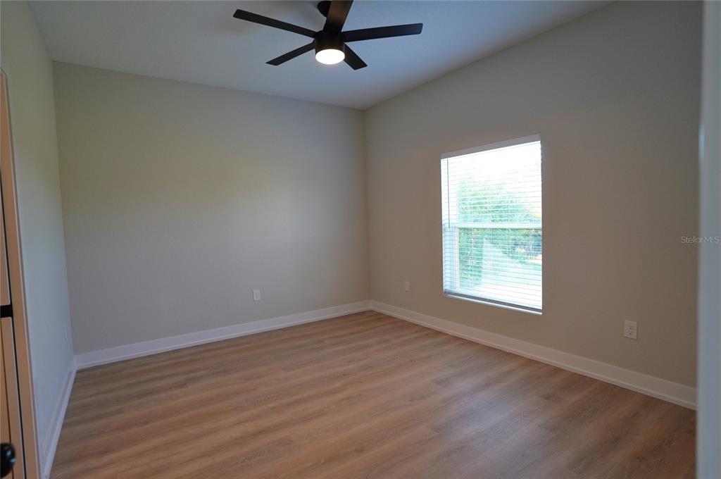 12032 Tetzel Avenue Port Charlotte, FL 33981 - Photo 16 of 32 an empty room with wooden floor fan and windows