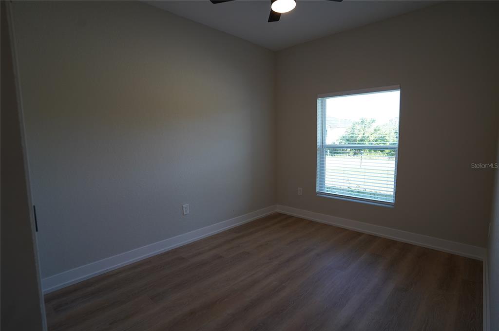12032 Tetzel Avenue Port Charlotte, FL 33981 - Photo 9 of 32 an empty room with wooden floor and windows