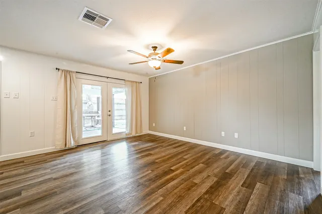 a view of an empty room with window and wooden floor