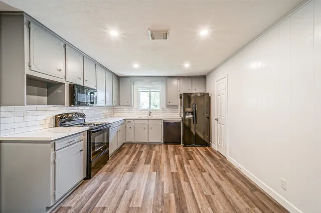 a kitchen with a sink a counter top space stainless steel appliances and cabinets