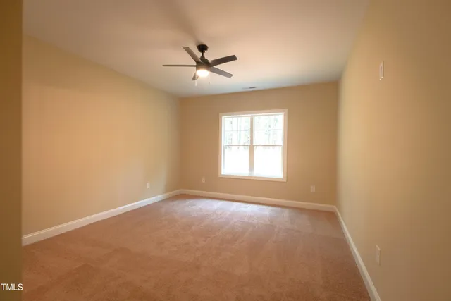 an empty room with chandelier fan and windows