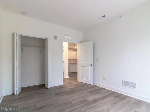 a view of an empty room with wooden floor & closet