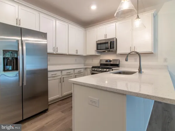 a kitchen with stainless steel appliances granite countertop a refrigerator a sink a stove a microwave oven with white cabinets