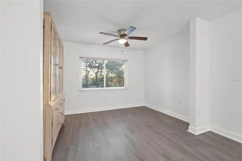 an empty room with wooden floor chandelier fan and windows