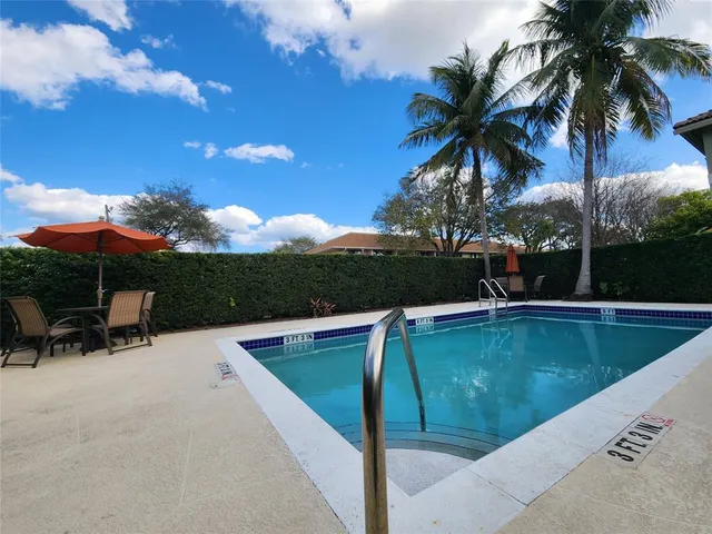a view of swimming pool with a table and chairs under an umbrella