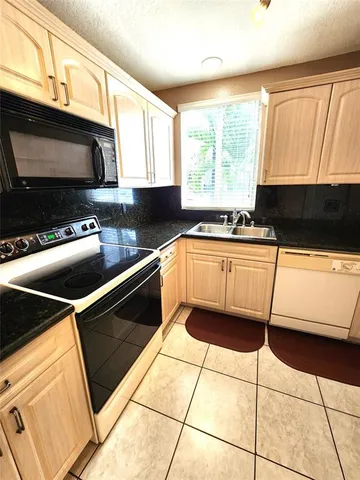 a kitchen with granite countertop a sink a stove a microwave and cabinets