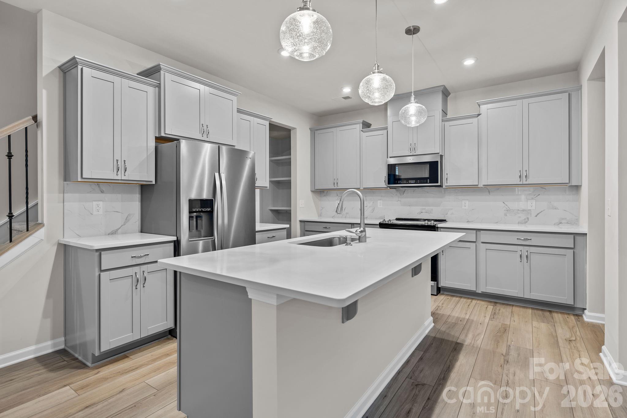 11246 Bartrams Way Charlotte, NC 28278 - Photo 9 of 31 a kitchen with kitchen island granite countertop a refrigerator a stove a sink and white cabinets