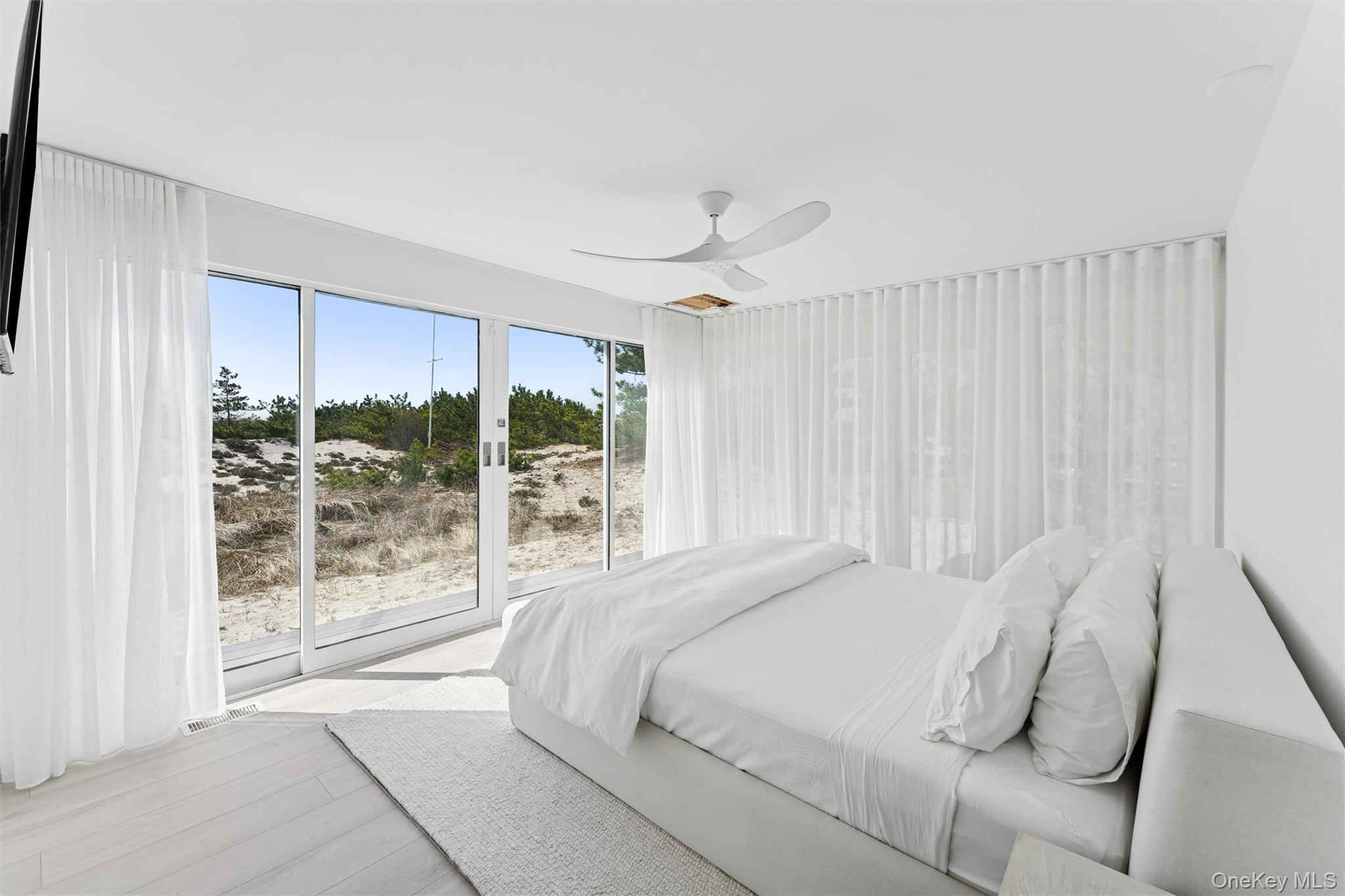 413 B Dune Road Westhampton Beach, NY 11978 - Photo 19 of 26 a bedroom with a large bed and a large window