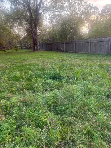 a view of a yard with a fence and trees