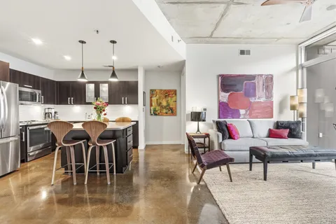 a living room with stainless steel appliances furniture and a kitchen view