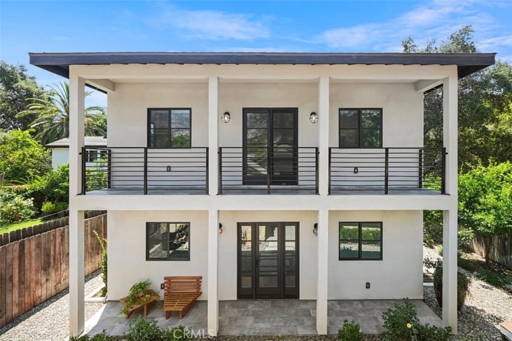 a view of a white house with large windows and potted plants