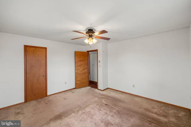 a view of an empty room with chandelier fan