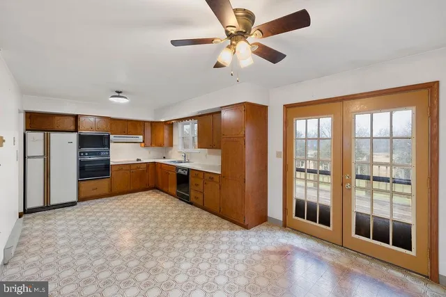 a large kitchen with stainless steel appliances a large window cabinets and a kitchen view