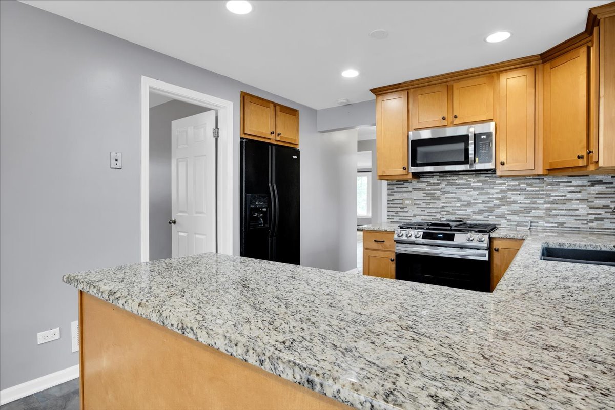 10822 Major Avenue Chicago Ridge, IL 60415 - Photo 19 of 30 a kitchen with stainless steel appliances kitchen island granite countertop a stove top oven microwave and refrigerator