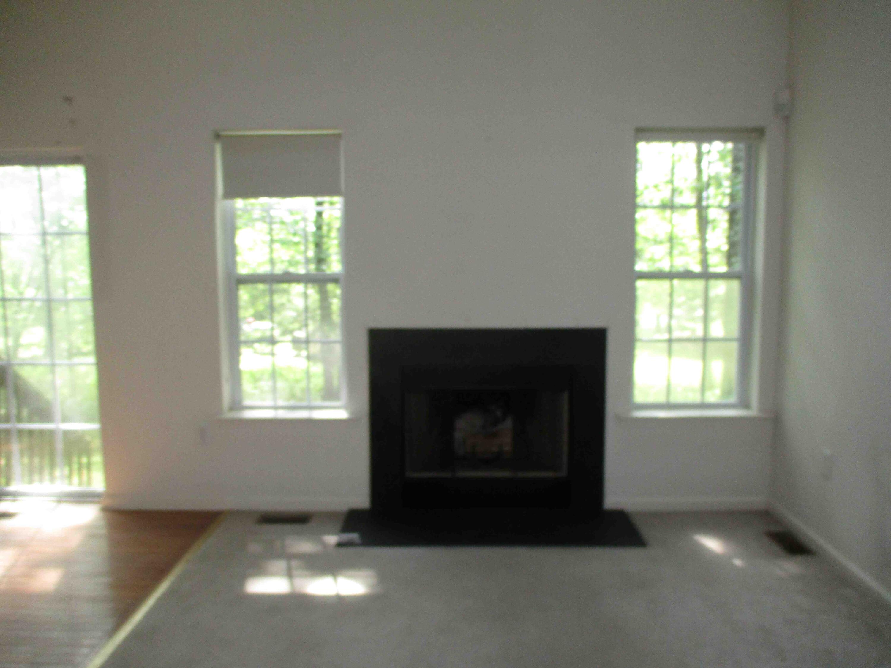 2113 Dorset Court Bushkill, PA 18324 - Photo 5 of 10 an empty room with a fireplace and windows