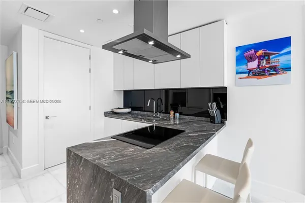 a kitchen with granite countertop a refrigerator and a stove top oven