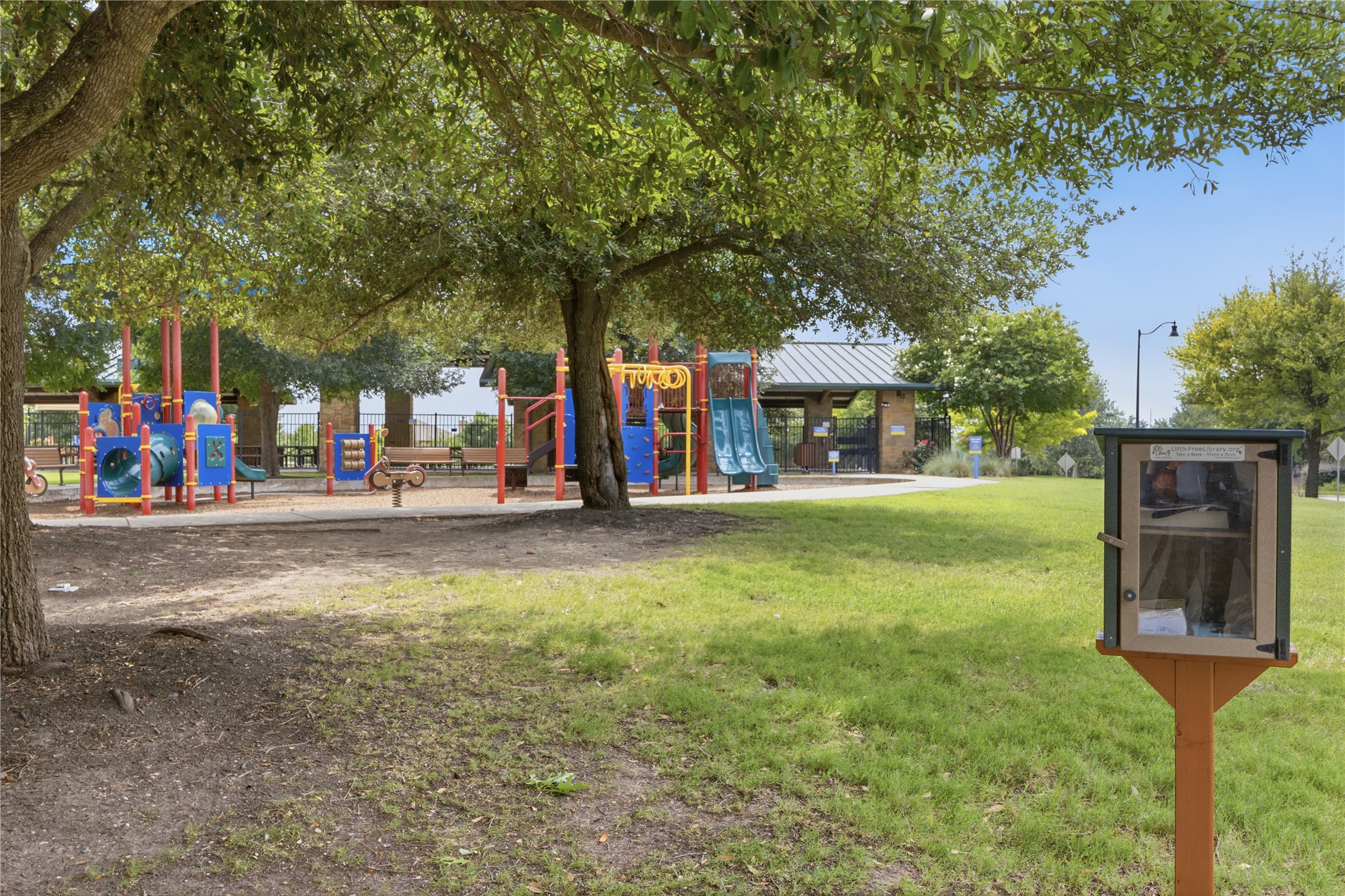 486 Pond View Pass Buda, TX 78610 - Photo 36 of 39 Community park featuring a colorful playground, paved walking paths, covered picnic area, mature trees providing shade, and a small community library box