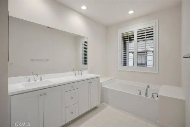a spacious bathroom with double vanity sink a bathtub and mirror