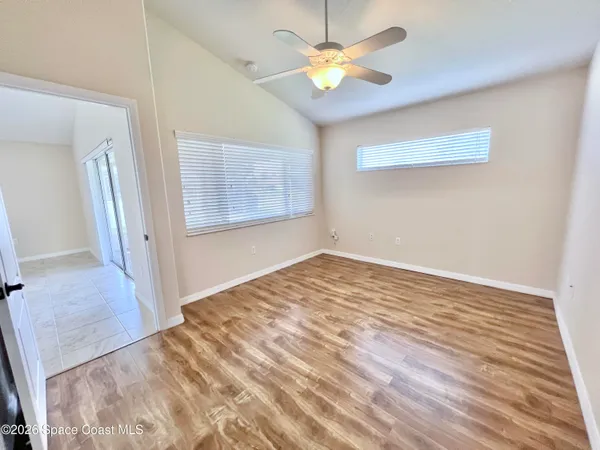a view of an empty room with chandelier fan and windows