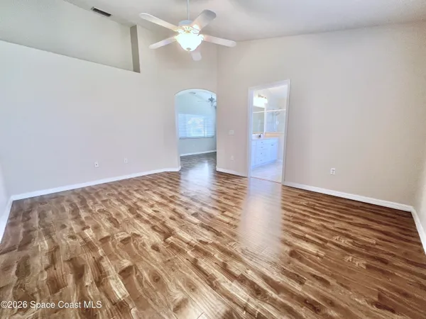 a view of empty room with wooden floor and fan