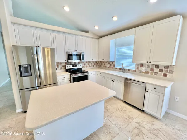 a kitchen with stainless steel appliances a refrigerator sink and microwave