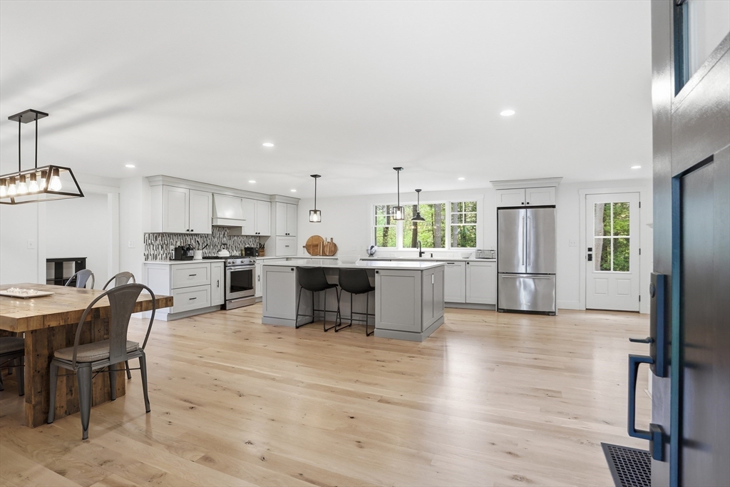 136 Holden Wood Road Concord, MA 01742 - Photo 7 of 31 a kitchen with stainless steel appliances kitchen island granite countertop a table chairs sink refrigerator and cabinets