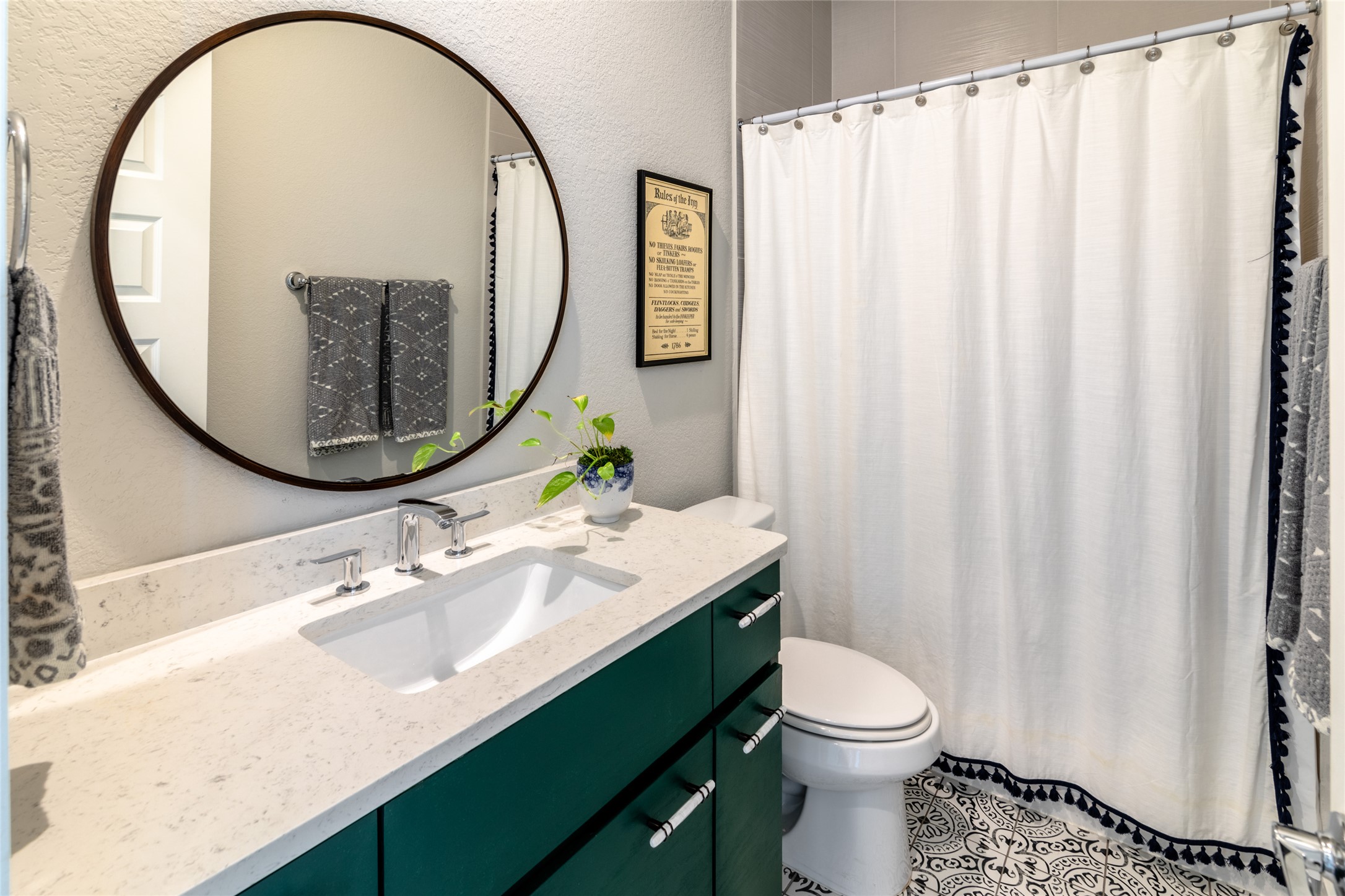 6025 Seville Drive Austin, TX 78724 - Photo 26 of 40 Second floor guest bathroom featuring a vanity with a white countertop and deep green cabinetry, an undermount sink with chrome fixtures, mirror, and patterned floor tiling
