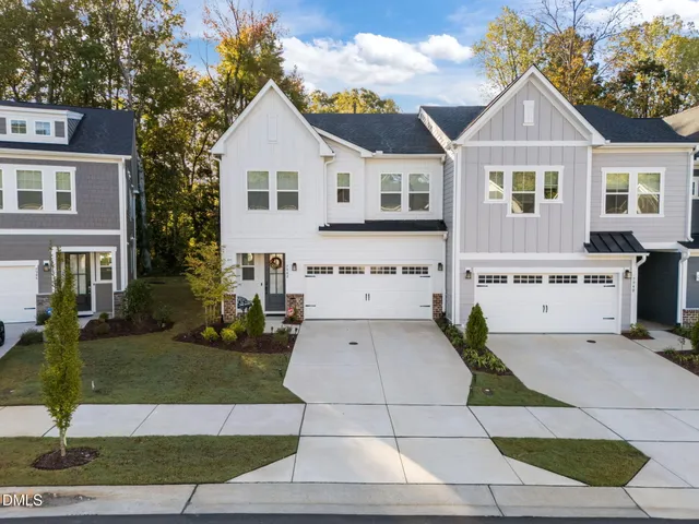 a view of white house with a yard and potted plants