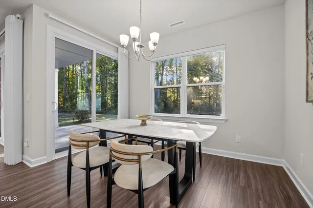 a dining room with wooden floor a chandelier a wooden table and chairs