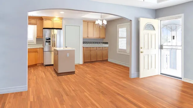 a view of a hallway with wooden floor and a kitchen