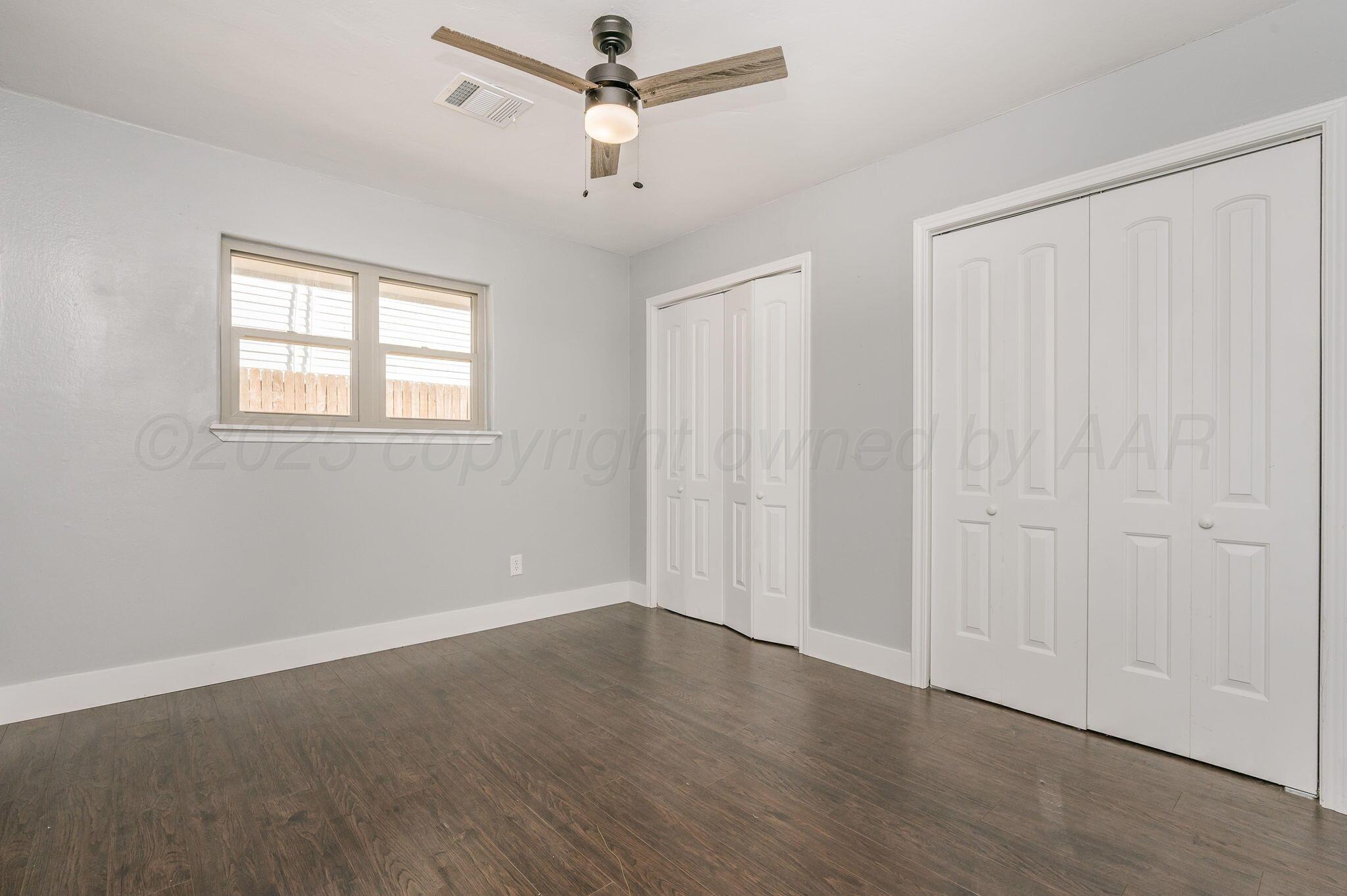 6218 Adirondack Trail Amarillo, TX 79106 - Photo 18 of 26 an empty room with wooden floor chandelier fan and windows